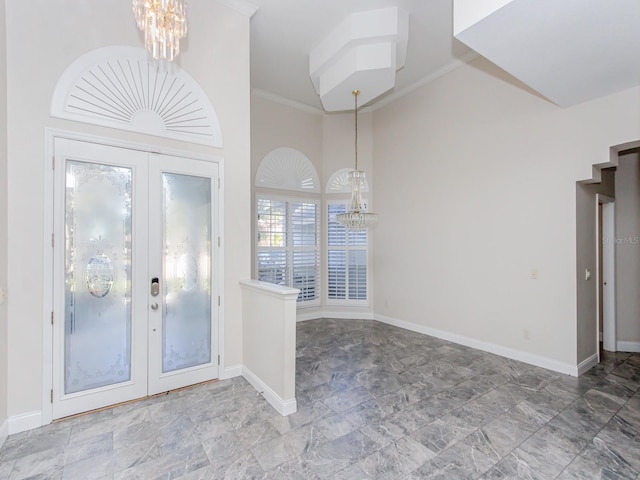 entrance foyer with crown molding, a towering ceiling, a notable chandelier, and french doors