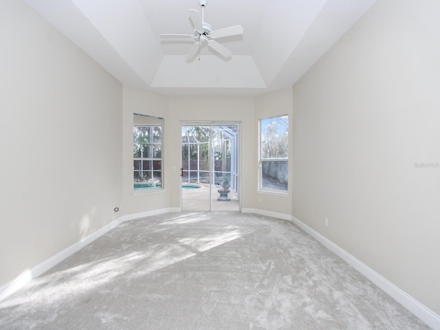 unfurnished room with a raised ceiling, light carpet, and ceiling fan