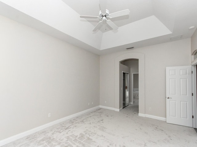 unfurnished bedroom featuring a raised ceiling, light colored carpet, and ceiling fan