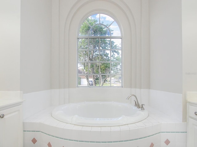 bathroom with tiled tub and vanity