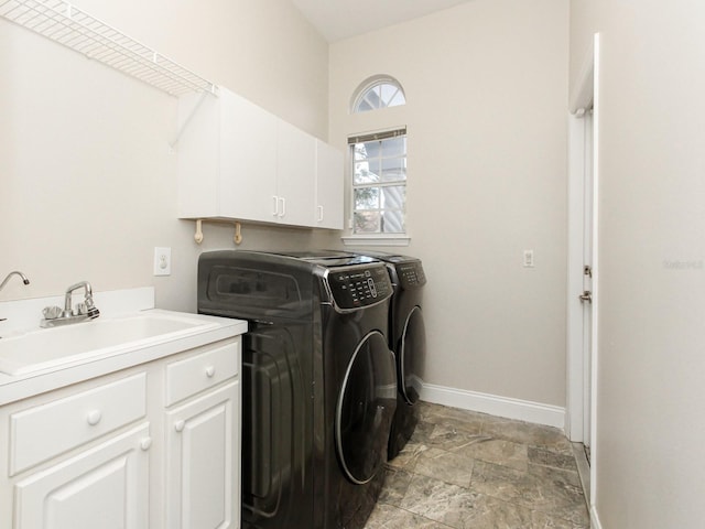 washroom with cabinets, washing machine and dryer, and sink