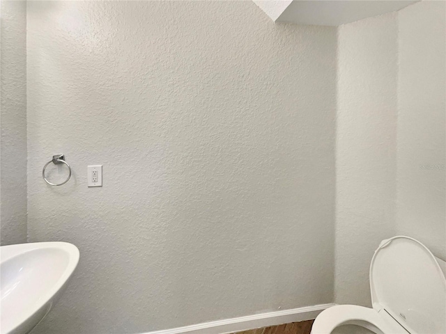 bathroom featuring wood-type flooring, toilet, and sink