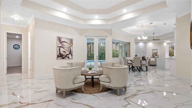 interior space with french doors, ornamental molding, a tray ceiling, and an inviting chandelier