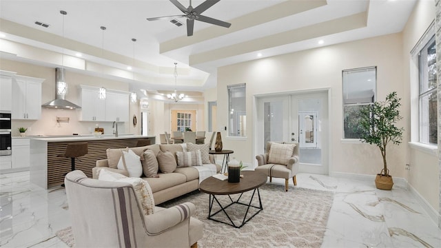 living room with plenty of natural light, sink, ceiling fan with notable chandelier, and a tray ceiling