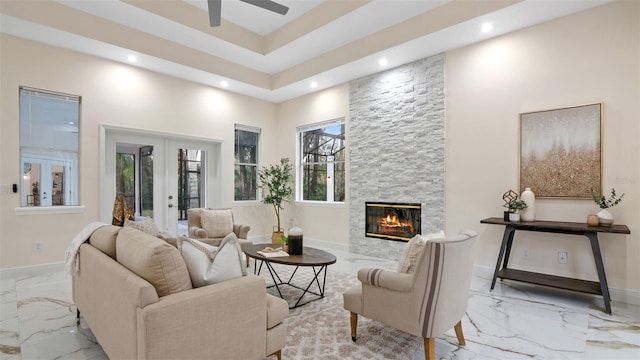 living room with a stone fireplace, ceiling fan, and french doors