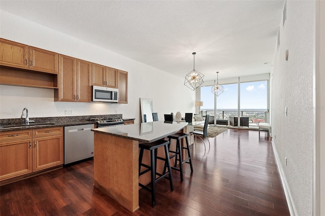 kitchen featuring appliances with stainless steel finishes, pendant lighting, sink, expansive windows, and a center island