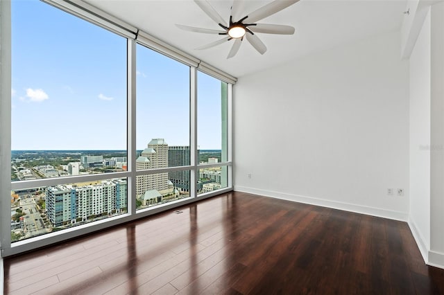 unfurnished room with hardwood / wood-style flooring, floor to ceiling windows, a healthy amount of sunlight, and ceiling fan