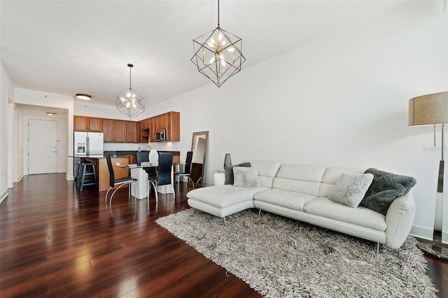 living room featuring dark wood-type flooring, a chandelier, and vaulted ceiling