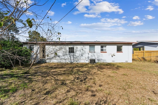 rear view of house featuring central AC unit and a lawn