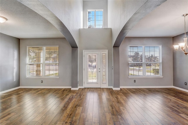 entryway featuring a high ceiling, an inviting chandelier, a wealth of natural light, and wood-type flooring