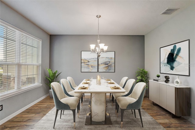 dining area featuring plenty of natural light, dark wood-type flooring, and a notable chandelier