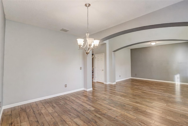 spare room with hardwood / wood-style flooring and an inviting chandelier