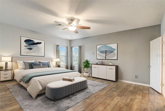 bedroom with hardwood / wood-style flooring, ceiling fan, and a textured ceiling