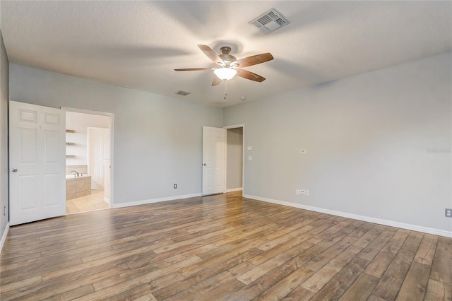 spare room featuring ceiling fan, light hardwood / wood-style flooring, and a textured ceiling