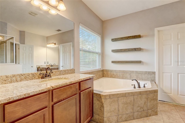 bathroom featuring vanity, a relaxing tiled tub, and tile patterned floors