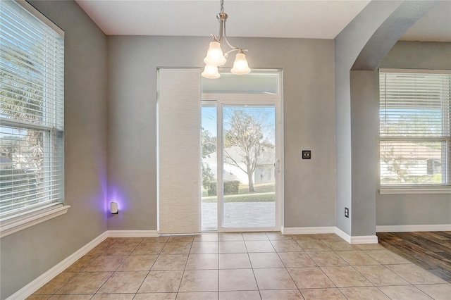 entryway featuring light tile patterned floors, a chandelier, and a wealth of natural light