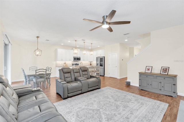 living room featuring light hardwood / wood-style floors and ceiling fan