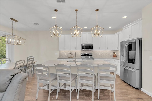 kitchen featuring stainless steel appliances, hanging light fixtures, sink, and white cabinets