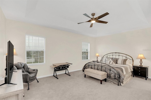 carpeted bedroom featuring ceiling fan and a tray ceiling