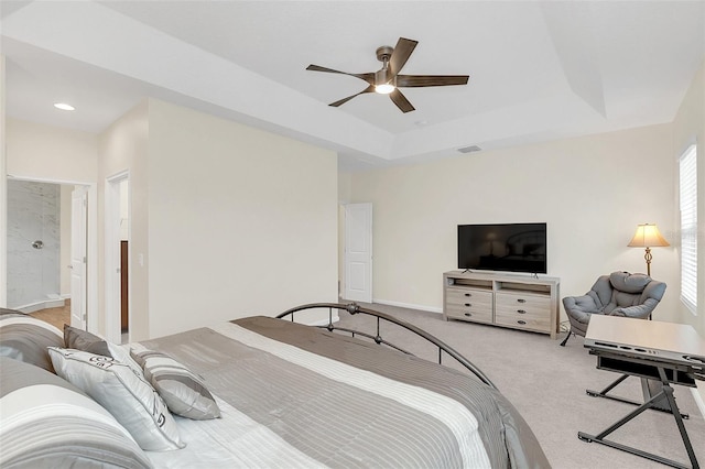 carpeted bedroom with ensuite bath, a raised ceiling, and ceiling fan