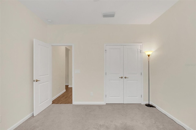 unfurnished bedroom with light carpet and a closet