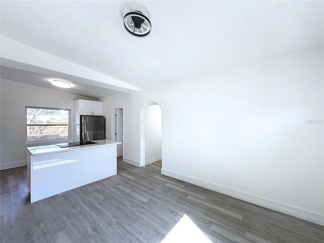 kitchen featuring lofted ceiling, dark hardwood / wood-style flooring, stainless steel fridge, and white cabinets