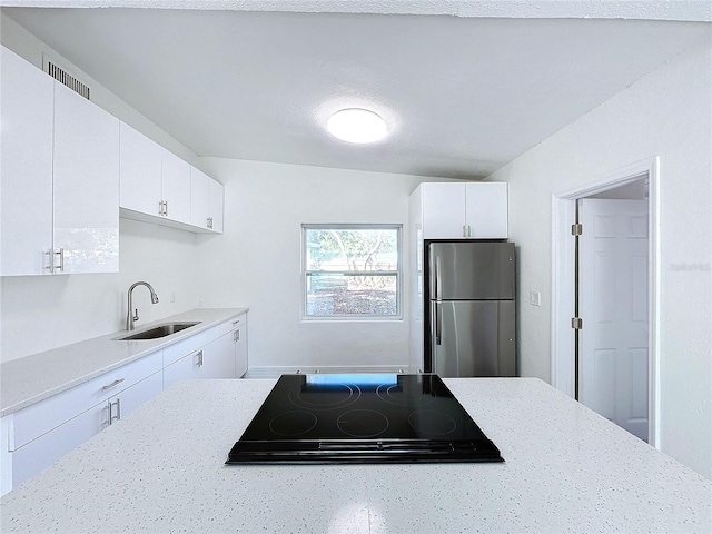 kitchen featuring stainless steel refrigerator, white cabinetry, black electric cooktop, and sink