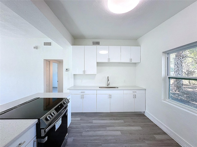 kitchen featuring stainless steel electric range oven, dark hardwood / wood-style floors, sink, white cabinets, and a textured ceiling