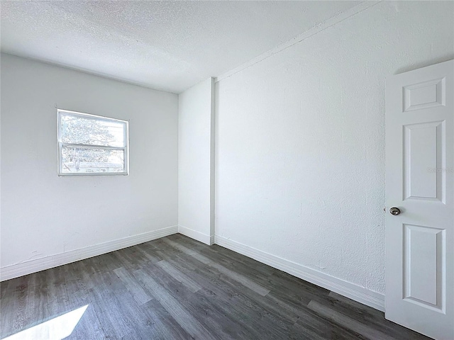 empty room with dark hardwood / wood-style flooring and a textured ceiling