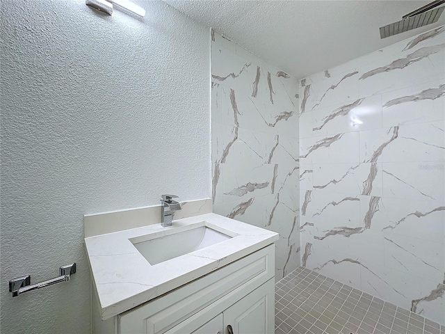 bathroom with tiled shower and vanity