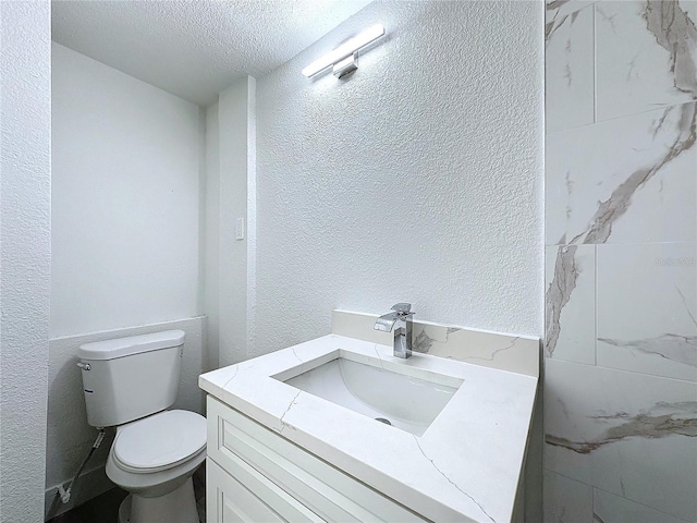 bathroom with vanity, a textured ceiling, and toilet