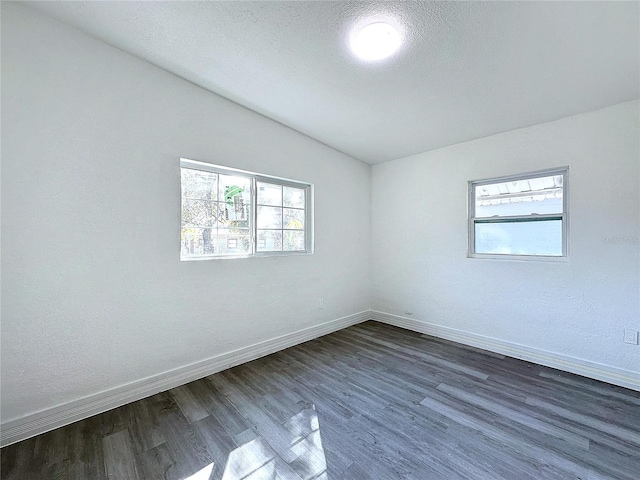 unfurnished room with dark hardwood / wood-style floors, vaulted ceiling, a textured ceiling, and a wealth of natural light