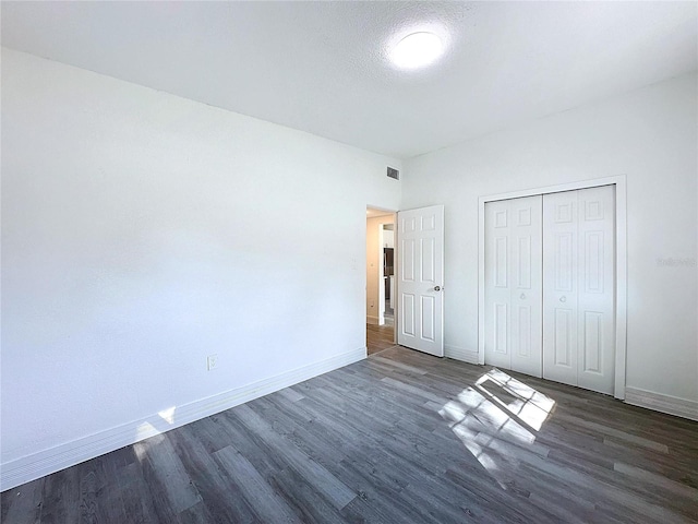 unfurnished bedroom featuring dark hardwood / wood-style flooring, a closet, and a textured ceiling