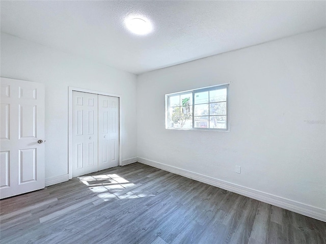 unfurnished bedroom with dark hardwood / wood-style floors, a textured ceiling, and a closet