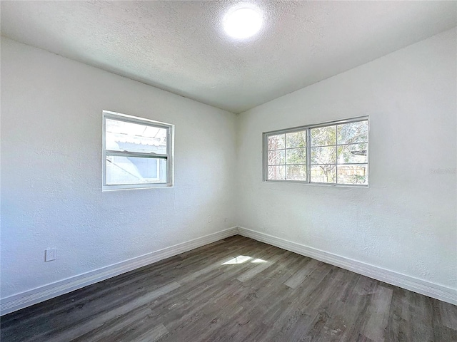 empty room featuring lofted ceiling, a textured ceiling, and dark hardwood / wood-style flooring