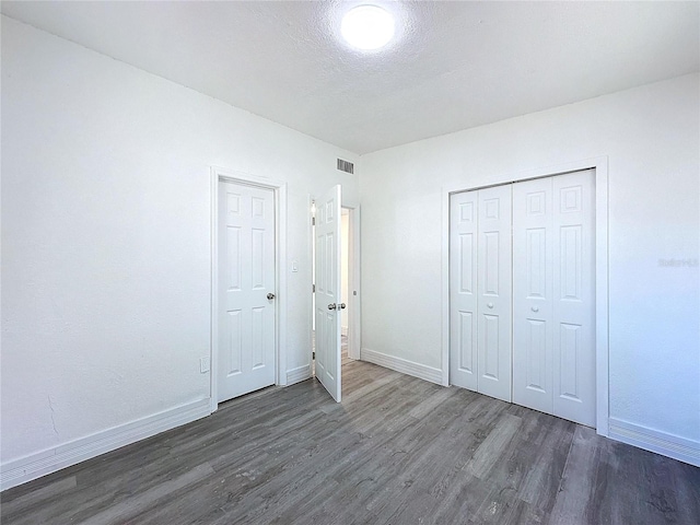 unfurnished bedroom featuring a closet, dark hardwood / wood-style floors, and a textured ceiling