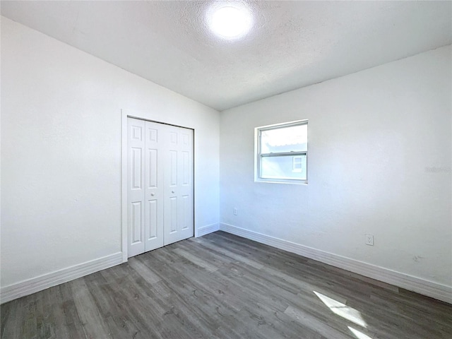 unfurnished bedroom featuring dark hardwood / wood-style floors, a closet, and a textured ceiling