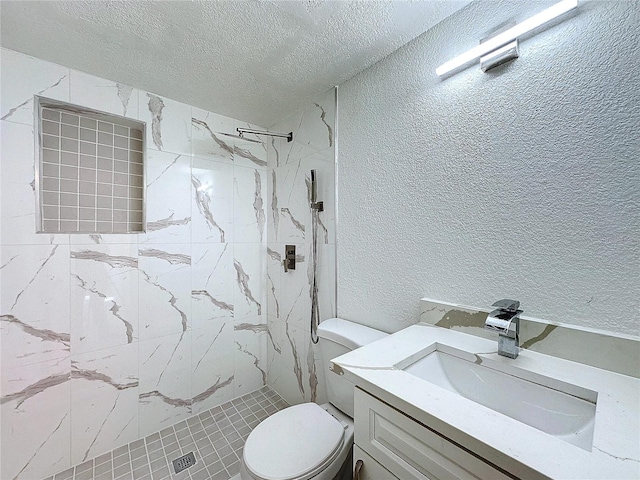 bathroom with a tile shower, vanity, a textured ceiling, and toilet