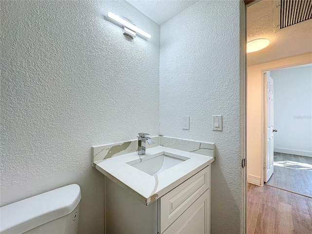 bathroom with hardwood / wood-style flooring, vanity, and toilet