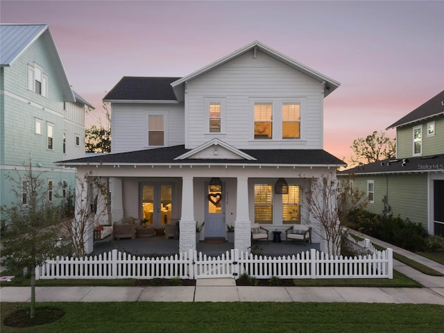 back house at dusk featuring french doors and covered porch