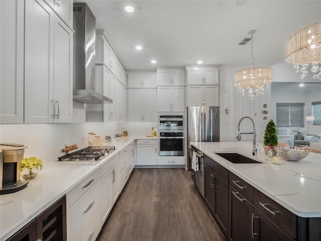 kitchen with white cabinetry, sink, decorative light fixtures, and wall chimney exhaust hood