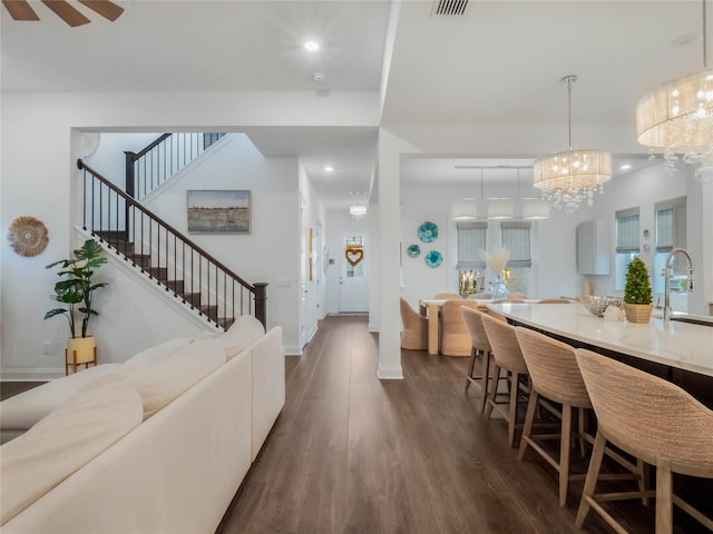 interior space featuring ceiling fan with notable chandelier, dark hardwood / wood-style flooring, and sink