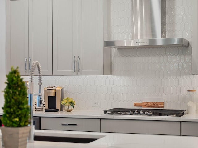 kitchen featuring stainless steel gas cooktop, decorative backsplash, and wall chimney exhaust hood