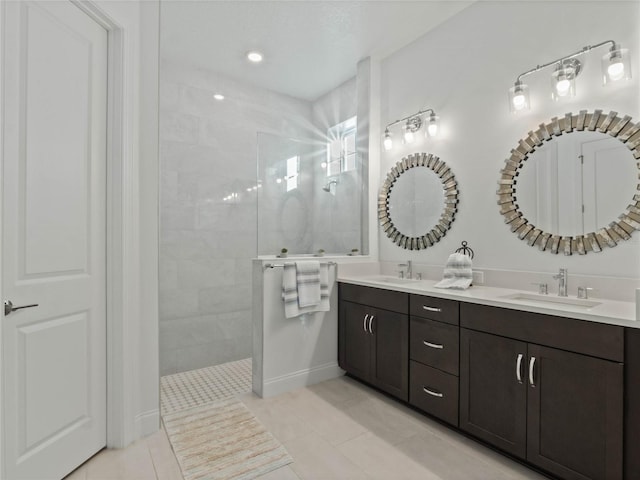 bathroom with tiled shower, vanity, and tile patterned flooring