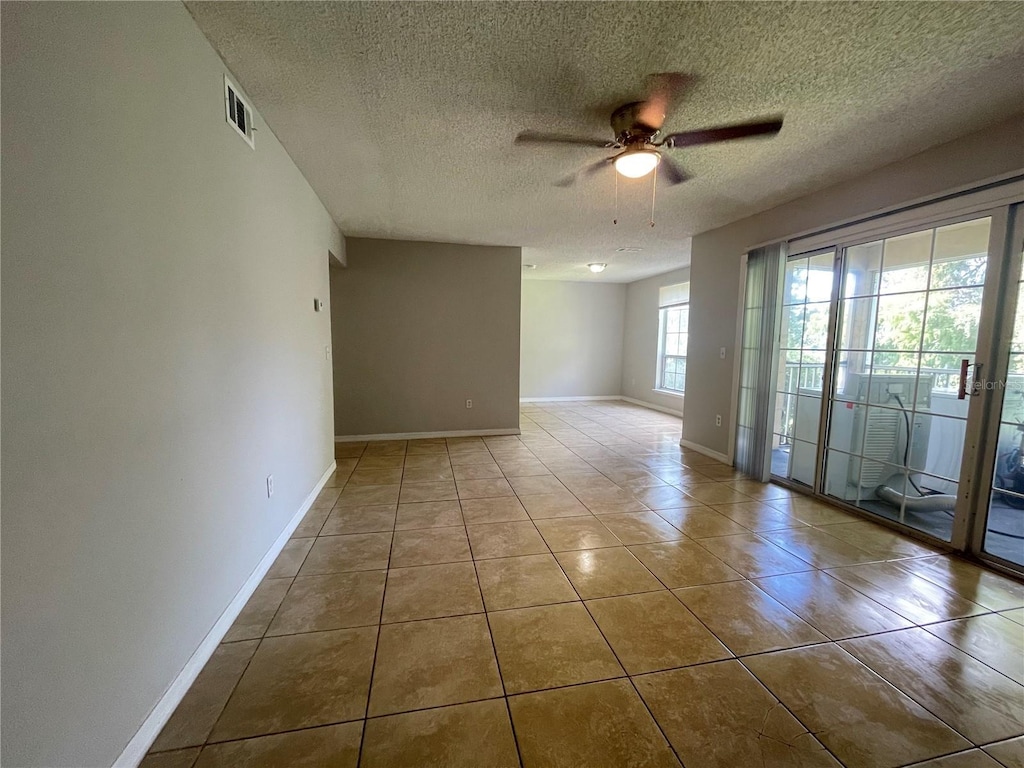 tiled empty room featuring ceiling fan and a textured ceiling