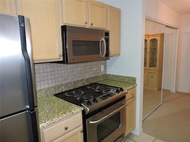 kitchen with light brown cabinetry, backsplash, light tile patterned floors, light stone counters, and stainless steel appliances