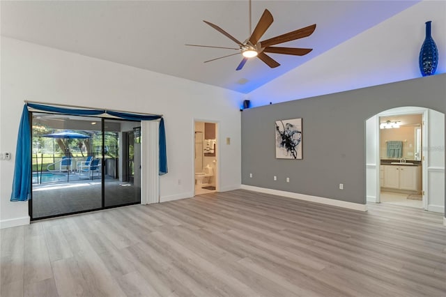 unfurnished living room with ceiling fan, sink, high vaulted ceiling, and light hardwood / wood-style flooring