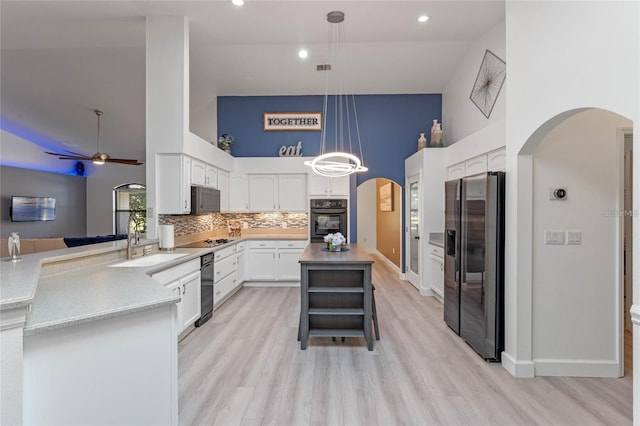 kitchen with appliances with stainless steel finishes, pendant lighting, tasteful backsplash, sink, and white cabinets