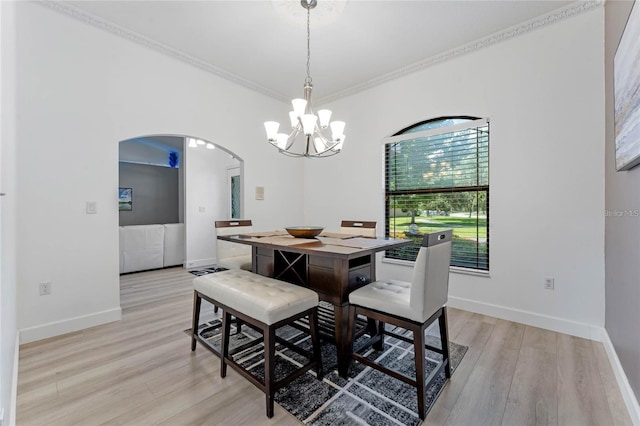 dining area with crown molding, a notable chandelier, and light hardwood / wood-style floors