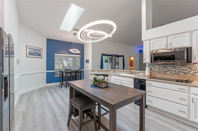 kitchen with pendant lighting, sink, white cabinetry, backsplash, and stainless steel appliances